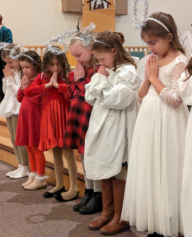 Little girls wearing halos and praying